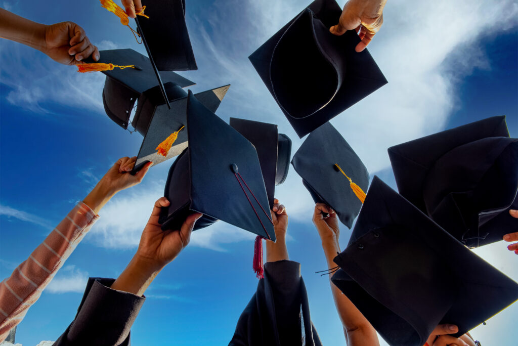 Graduates throwing graduation hats Up in the sky after finishing university.